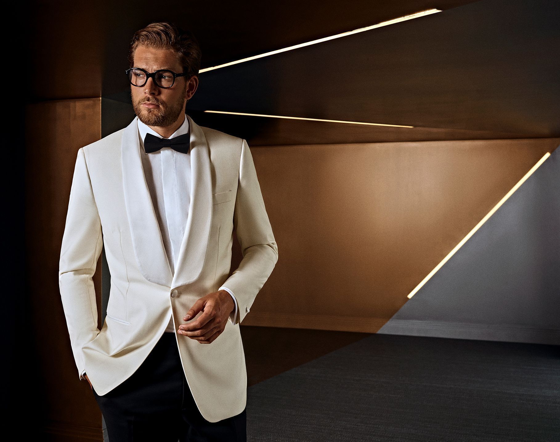 Man in stylish white tuxedo with black bow-tie, custom made occasion wear for men